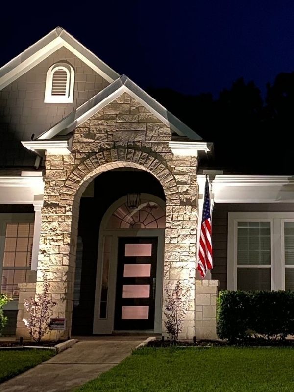 A residential home with an American flag and gorgeous outdoor lighting.