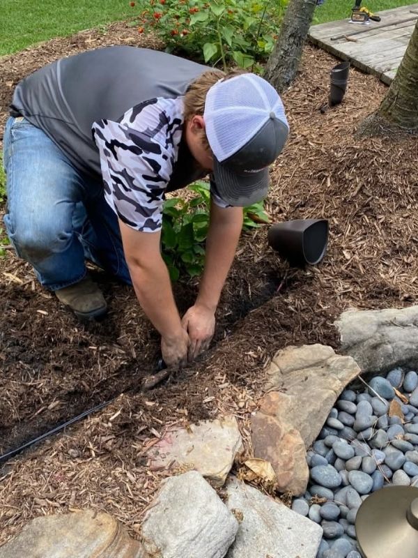 A man is working on installing landscape lighting. 
